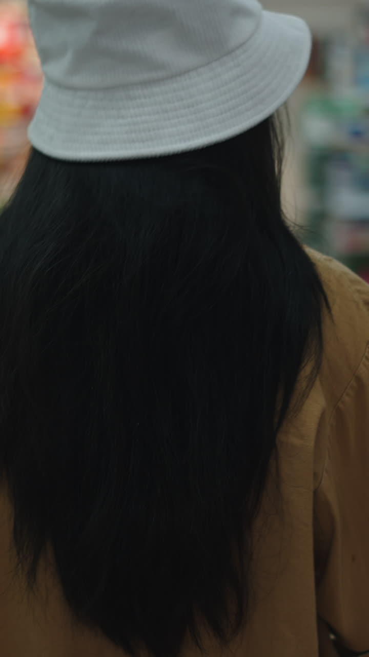 Wanita berambut hitam mengenakan topi dan mantel