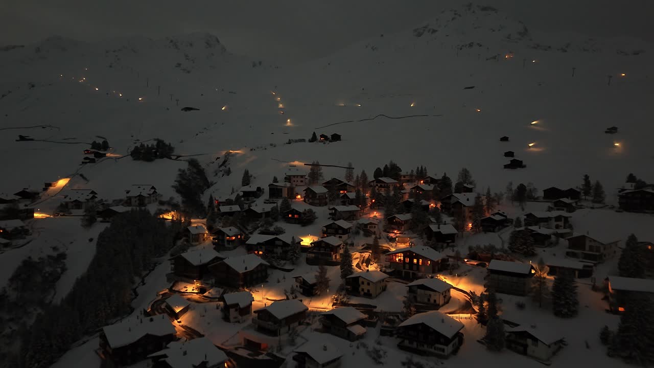 tomada aérea de aproximación de la ciudad de arosa en la montaña nevada de noche en suiza