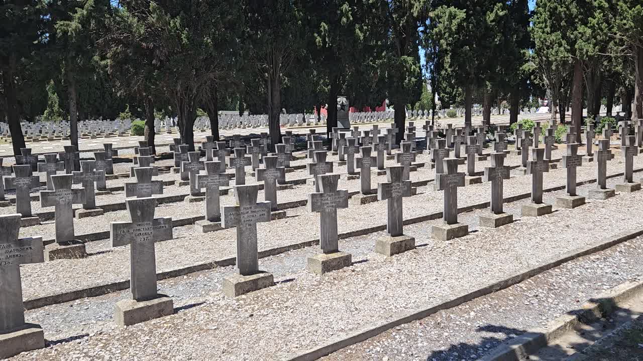 Rows of stone crosses mark the graves of Serbian soldiers at Zeitenlik military cemetery in Thessaloniki, Greece, surrounded by tall cypress trees in a solemn and peaceful atmosphere