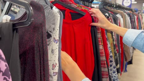 close-up of women’s hands selecting used clothes on hangers in a thrift store. poverty. used clothes from europe and america. black friday