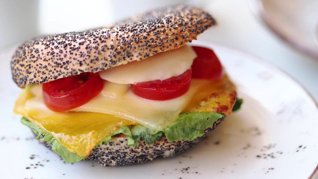 Sandwich con bagel ai semi di papavero appena preparato, con formaggio e pomodoro