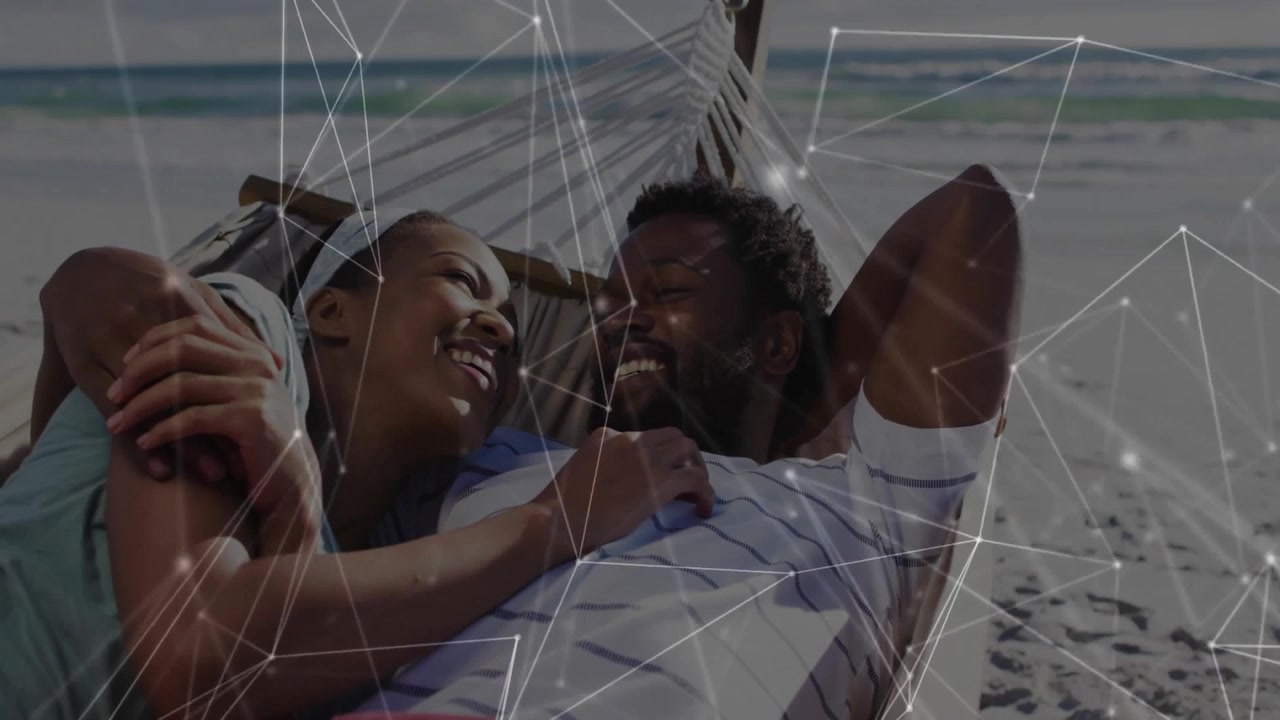 couple lounging on hammock near beach shoreline, showcasing technology network overlay