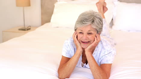 Happy-senior-woman-lying-on-her-bed