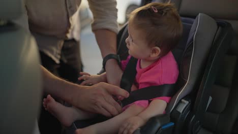 a father buckles his baby girl into her car seat.