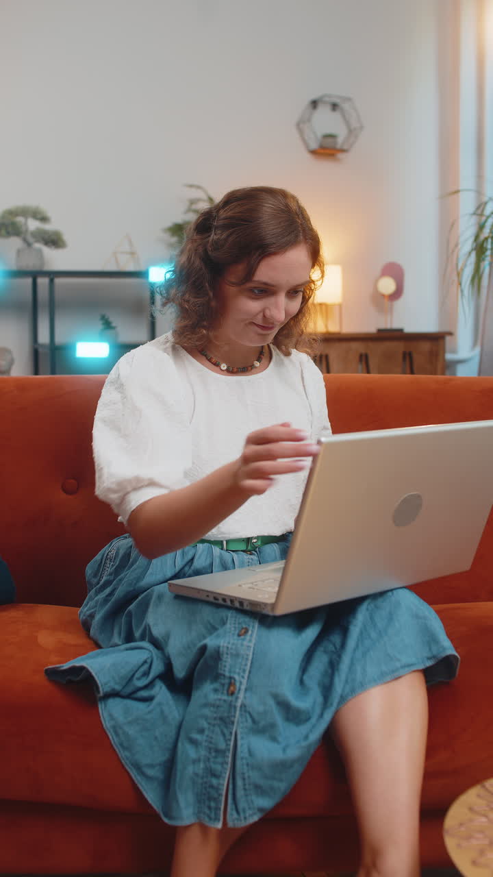 feliz mujer caucásica sentada en el sofá cerrando la computadora portátil después de terminar el trabajo en la sala de estar en casa