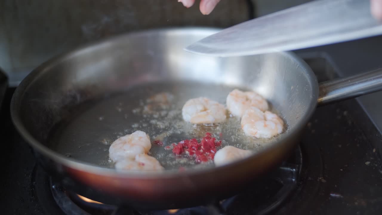 셰프가 야외 그릴에서 새우와 함께 파스타를 요리하고 있습니다.