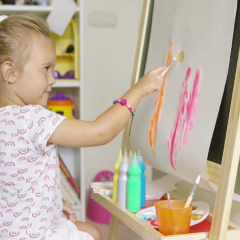 cute little blond girl painting with watercolors