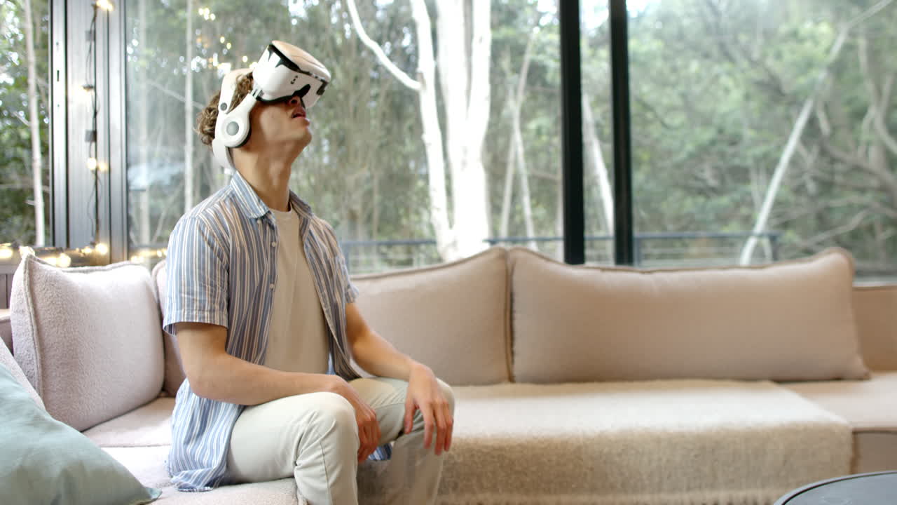Exploring virtual reality, young man using VR headset at home, feeling amazed, copy space