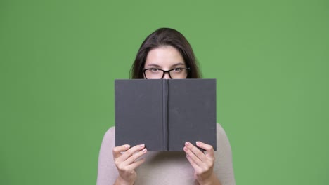 young beautiful woman hiding behind book