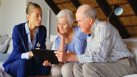 Front-view-of-Caucasian-senior-couple-discussing-over-clipboard-with-female-doctor-at-comfortable-co
