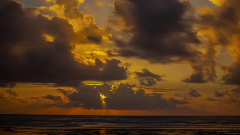 Goldene-Sonnenstrahlen-Hinter-Dunklen-Wolken,-Die-Sich-Am-Himmel-über-Dem-Meer-Bewegen