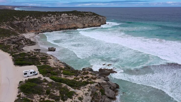 Vista aérea de Pennington Bay en Kangaroo Island con una furgoneta camper blanca, olas y la costa, Australia Meridional