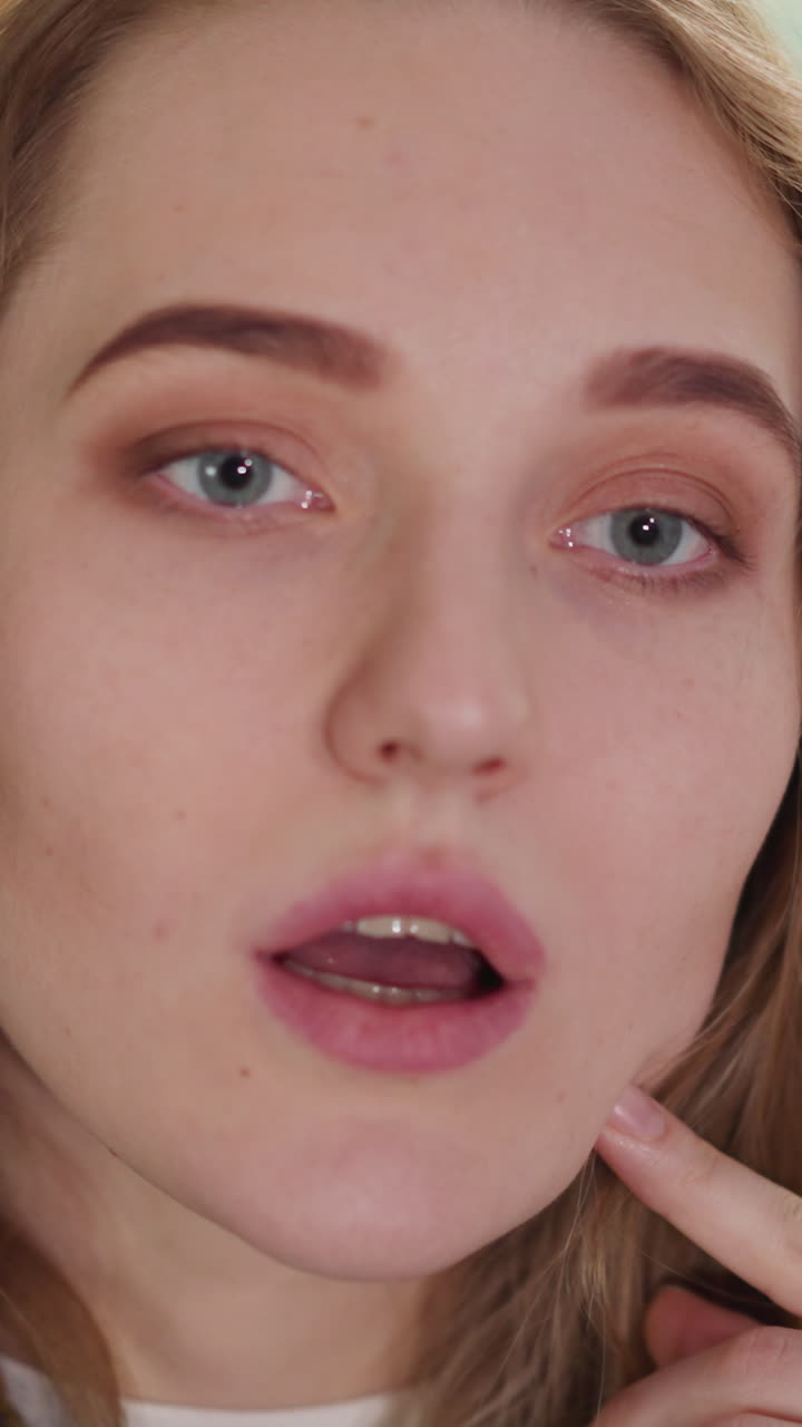 una mujer rubia sigue y comenta un video emocional a través de la televisión en la sala de estar en cámara lenta.