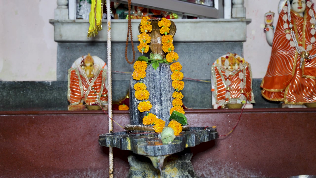 Shiva Lingam decorato con fiori in un tempio indù durante il sacro rituale di preghiera Shivaratri