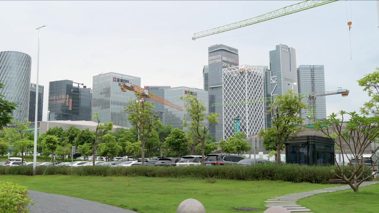 O horizonte de Shenzhen ostenta arranha-céus modernos e projetos de construção em andamento. Guindastes se elevam, sinalizando crescimento, enquanto uma rua paisagística exibe a vida urbana dinâmica da cidade na China.