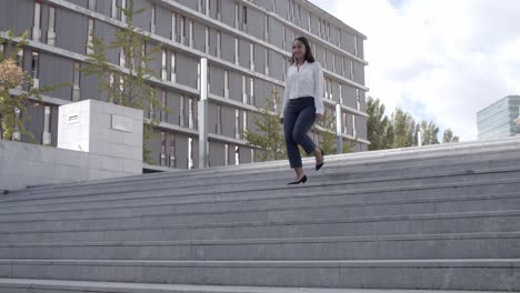 una joven mujer de negocios sonriente bajando las escaleras