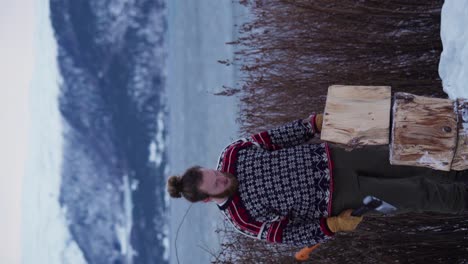 Vertical-Shot-Of-A-Man-Chopping-Wood-With-Axe-In-Winter