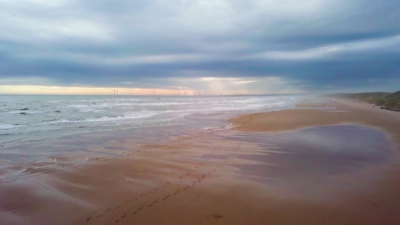 Serene beach view in Scotland, gentle waves washing up on golden sand