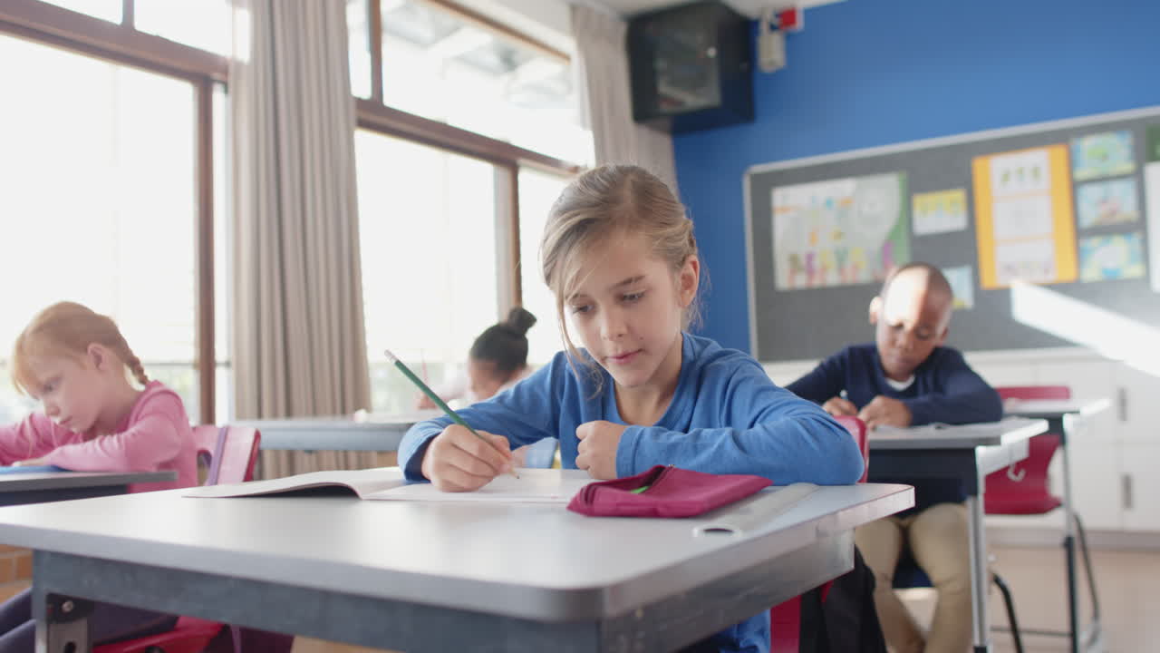In school, girl writing in notebook while concentrating in classroom