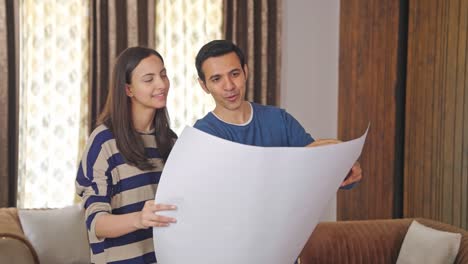 hombre indio feliz explicando el plan de la casa a su esposa