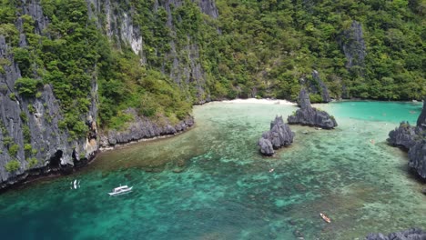 Aerial-pan-across-tourists-vacationing-at-cadlao-lagoon-exploring-reef-and-bay