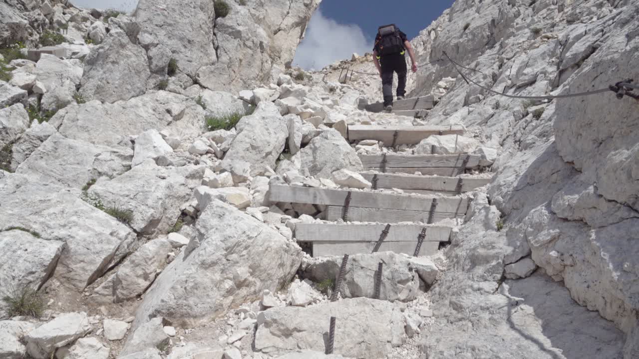 A hiker on stony steps of a hiking trail leading towards the summit of Mount Weisshorn - Corno Bianco, South Tyrol, Italy