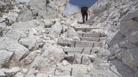 a hiker on stony steps of a hiking trail leading towards the summit of mount weisshorn - corno bianco, south tyrol, italy