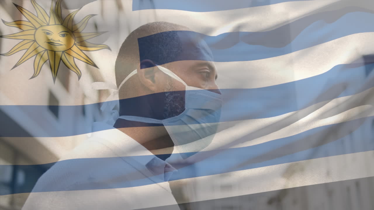 코로나 19 대유행 기간 동안 얼굴 마스크를 쓰고 있는 남성 위에 울려 퍼지는 우루과이 국기의 애니메이션