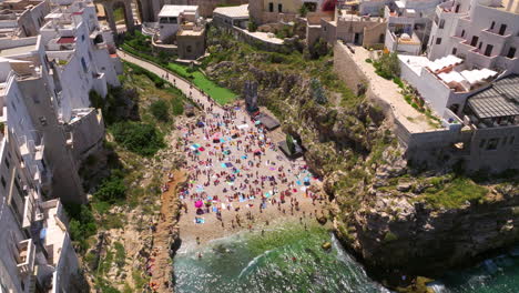 Aerial-View-Of-Tourists-At-Lama-Monachile-Beach-In-Polignano-a-Mare,-Italy---Drone-Shot