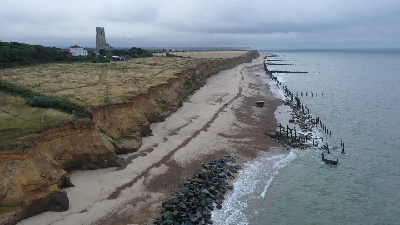 imágenes aéreas en movimiento lento a lo largo de la marea que llega a las defensas marinas hacia la iglesia
