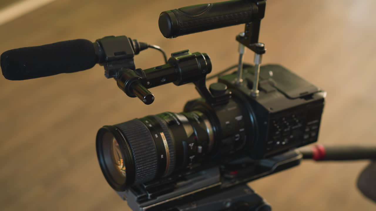 cameraman adjusting camera plate on tripod for filming, focusing on lens and setup, ensuring professional equipment is ready for video production in studio, hand controlling camera movement
