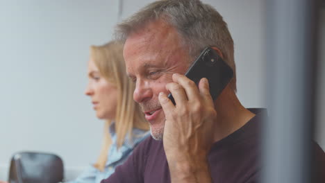 customers in coffee shop window working on laptops and making call on mobile phone