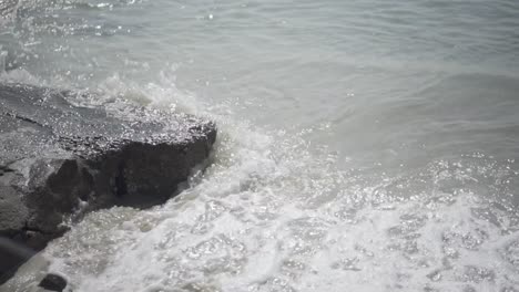 waves crashing on rock and washing the sand