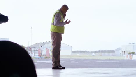 ingeniero masculino hablando por teléfono móvil en el hangar 4k