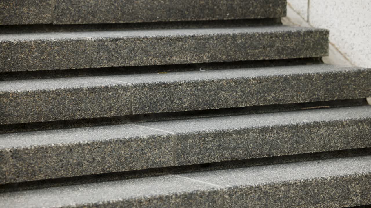Los peatones vienen de la derecha y suben escalones de hormigón texturizado para llegar a la entrada del edificio