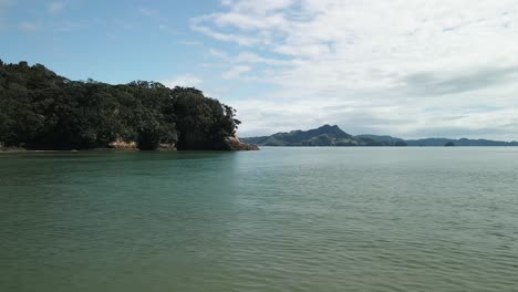 Drone-flying-low-across-glassy-water-around-Shakespeare-cliff-in-New-Zealand-along-the-Coromandel-Peninsula