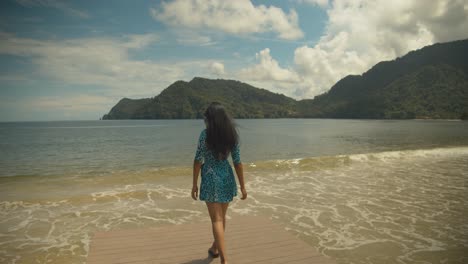 Modelo-Venezolana-Caminando-En-Un-Jetti-Con-Olas-Rompiendo-En-La-Costa-Y-Su-Cabello-Ondeando-En-El-Viento