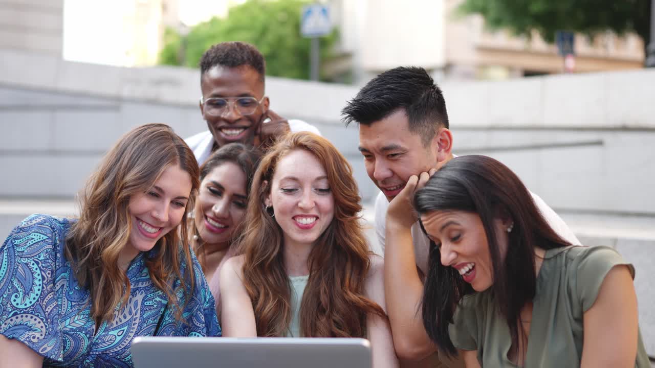 Diverse Group of Young Adults Laughing While Looking at a Laptop Together