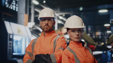 confident plant engineers posing manufacturing workshop in helmets close up.