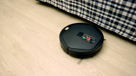 gato negro caminando detrás de una aspiradora robótica limpiando el piso. 4k