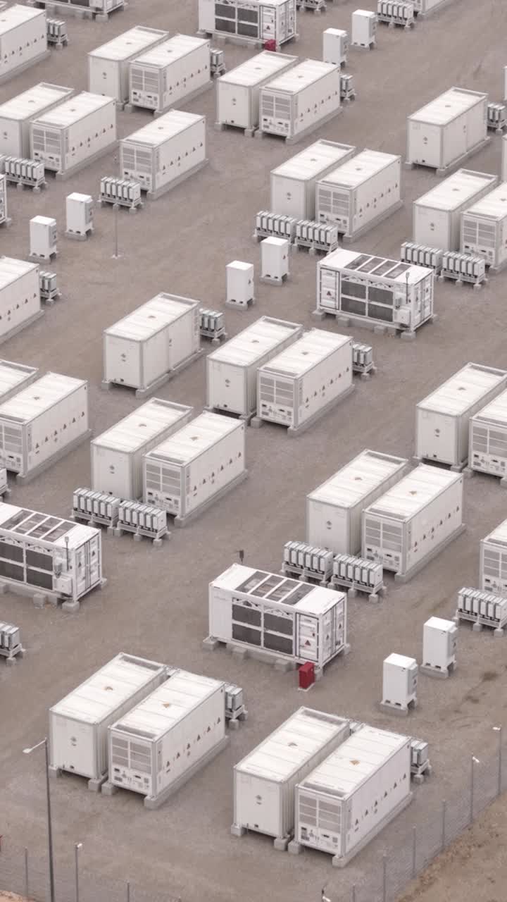 Ripresa aerea con drone di un impianto di stoccaggio di energia rinnovabile avvolto nella nebbia, che mostra unità batteria e infrastrutture, evidenziando l'accumulo di elettricità sostenibile e le condizioni atmosferiche.