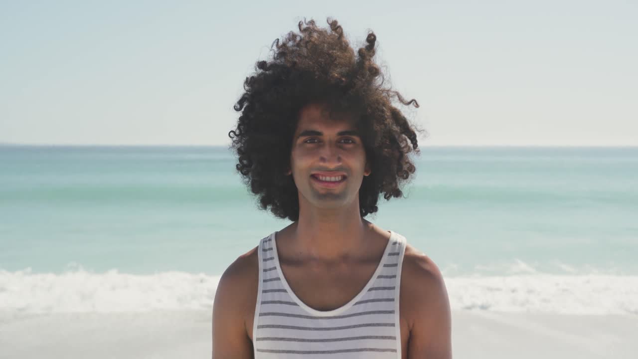Uomo di etnia mista che guarda la fotocamera in spiaggia
