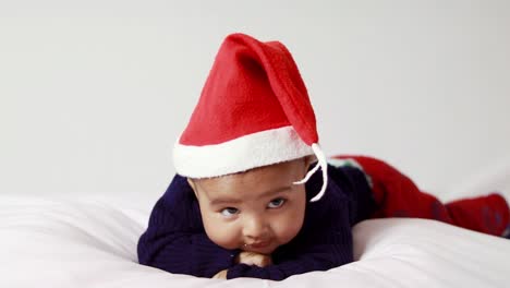 Niño-Pequeño-Con-Gorra-Roja-De-Navidad-Mintiendo-Linda-Expresión-Facial-Con-Fondo-Blanco-En-El-Interior