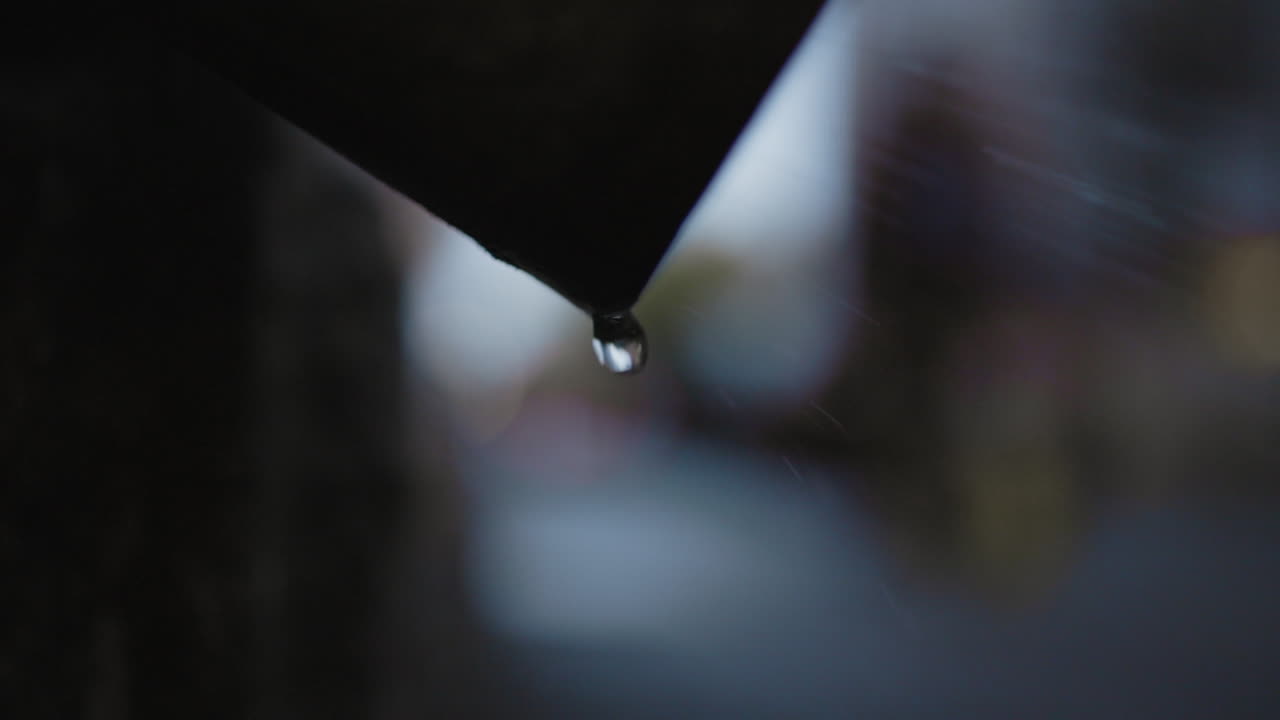 gotas de agua de un objeto recortado con gente caminando por el fondo borroso