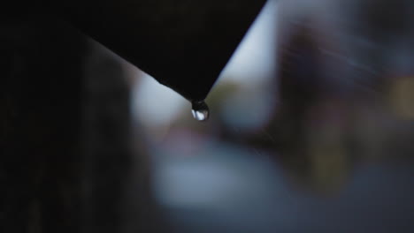 water drips from a silhouetted object with people walking through the blurred background