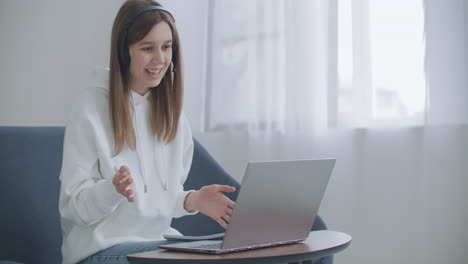 woman-is-working-remotely-by-internet.-Happy-young-business-woman-wears-headset-talks-to-web-camera-making-distance-online-video-conference-call.-Female-internet-teacher-doing-distant-chat-working