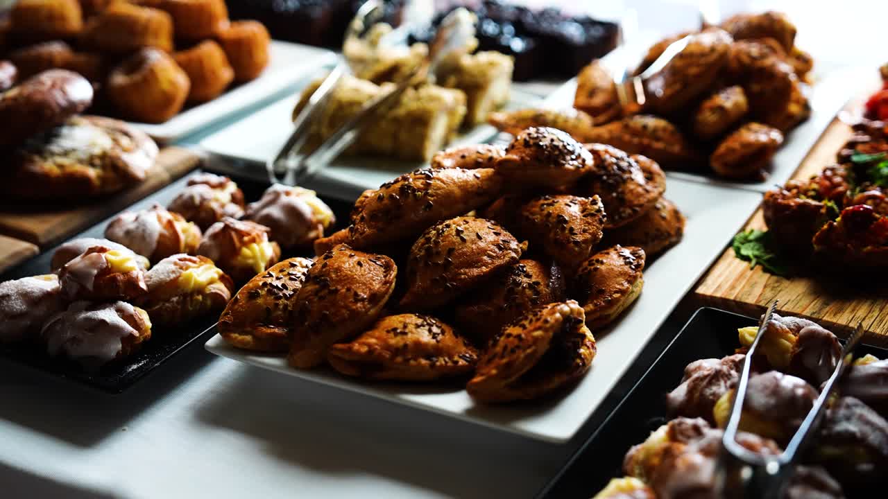 Varietà di prodotti da forno su un tavolo luminoso per eventi al chiuso, panini salati e dolci