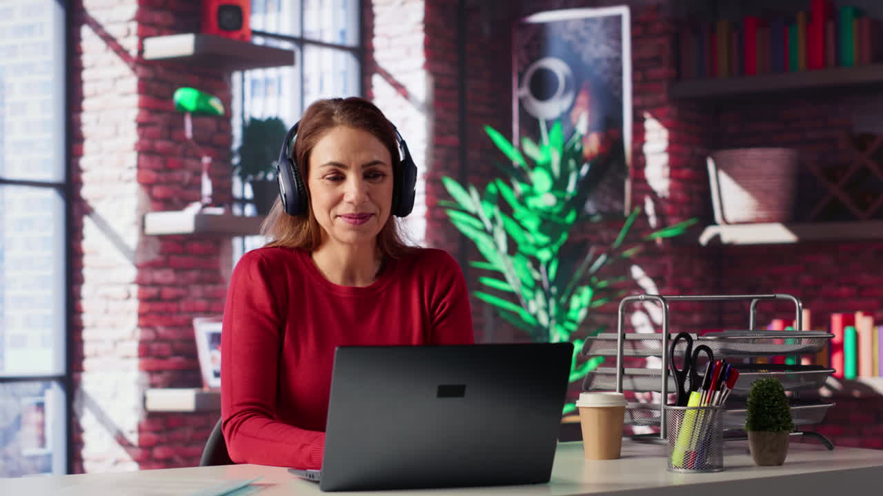 Woman working on laptop with headphones in office