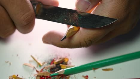 Footage-of-hands-slowly-sharpening-a-pencil-and-some-coloured-pencils-with-a-sharp-knife