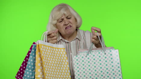 abuela sosteniendo bolsas de compras, regocijándose de los descuentos en la tienda, disfrutando de las compras con precios bajos